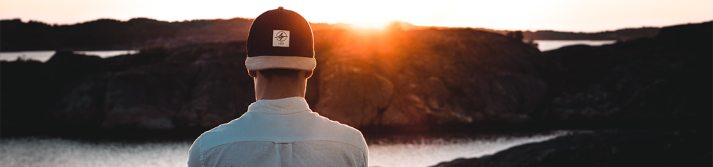 Imagem de um homem de costas para a câmera olhando o pôr do Sol.