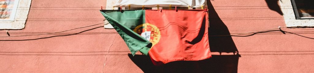 Foto de uma bandeira de Portugal na parede de uma casa.