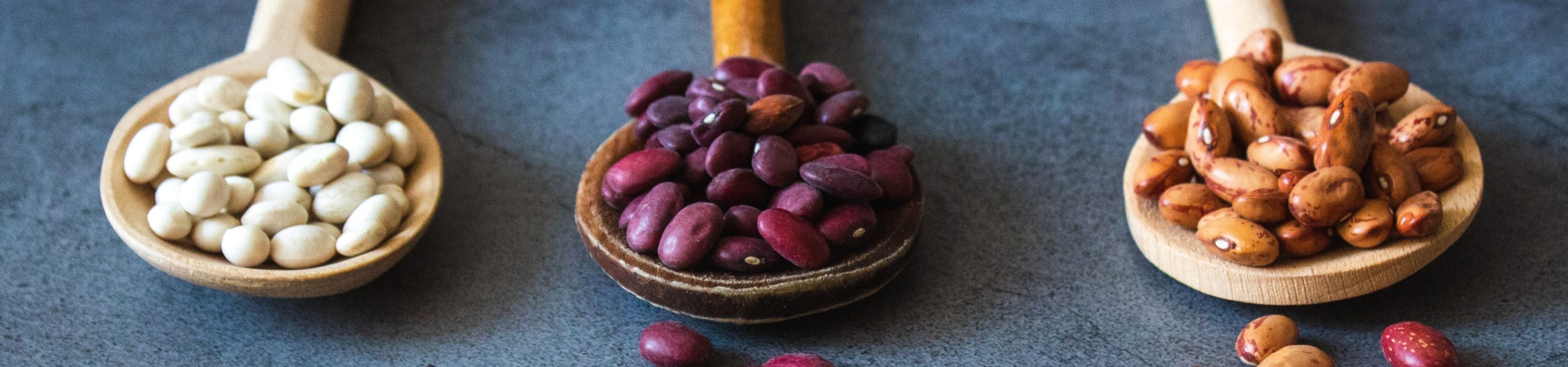 Imagem de colheres com diferentes tipos de feijão.