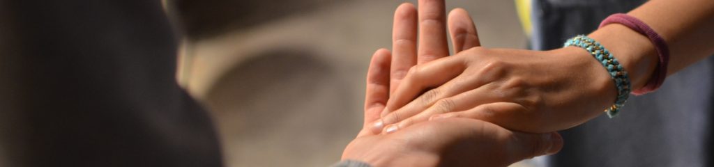 Imagem da palma da mão de um homem sob a mão de uma mulher.