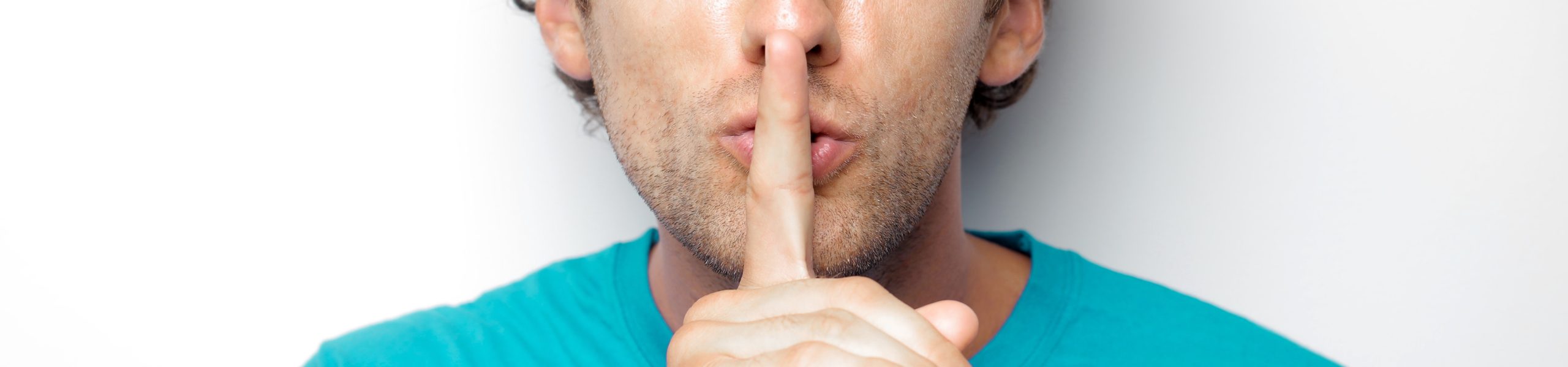 Imagem de um homem com o dedo indicador sobre os lábios, fazendo gesto de silêncio.