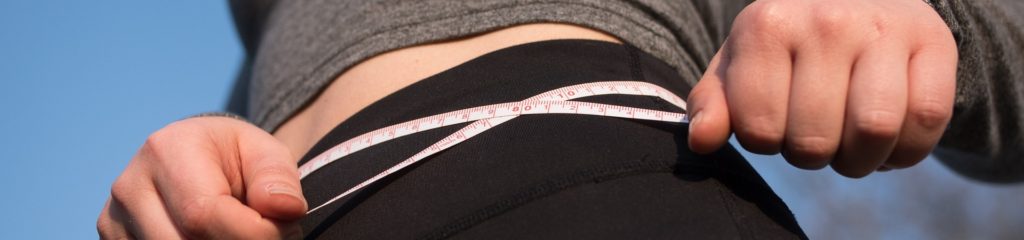 Imagem de uma mulher com uma fita métrica sobre o quadril.