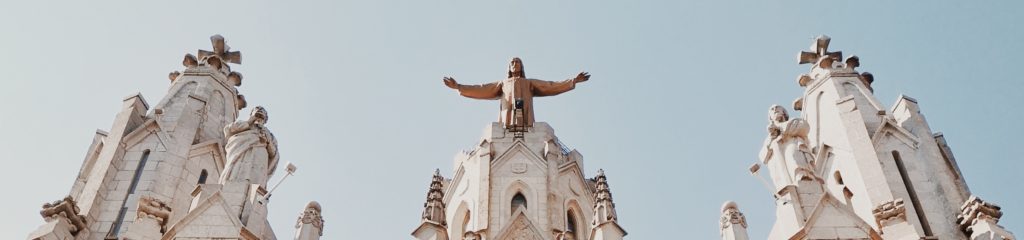 Imagem das torres de uma igreja de blocos brancos, com estátuas de santos.