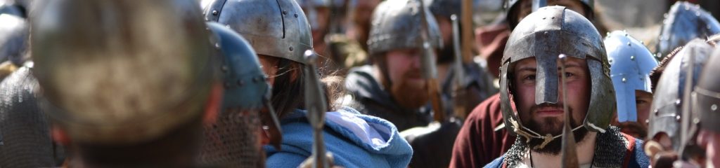 Imagem de vários homens vestindo armaduras e empunhando espadas.