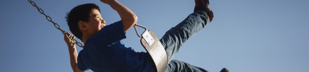 Imagem de um menino sorridente em um balanço.