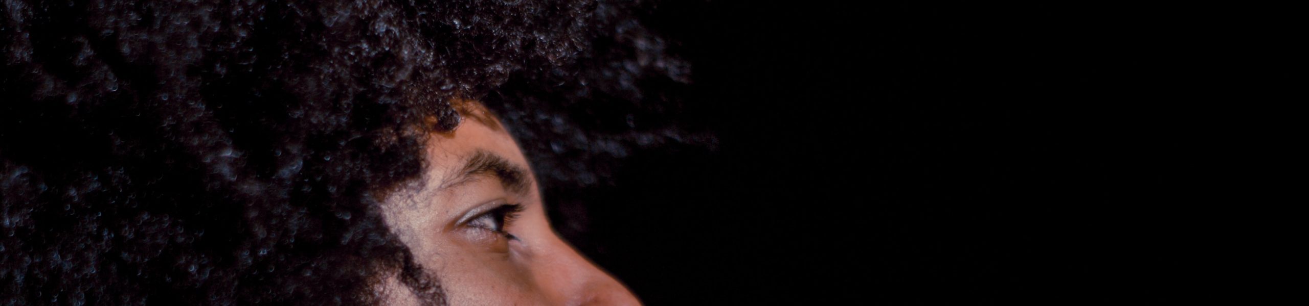 Imagem de uma pessoa de perfil, com destaque para um dos olhos, sobrancelha e cabelo.