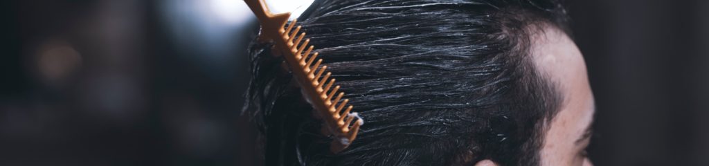 Imagem de um homem, de cabelo pretos, sendo penteado.