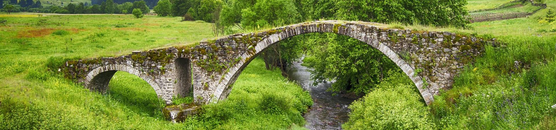 Ponte de pedra sobre um pequeno córrego.