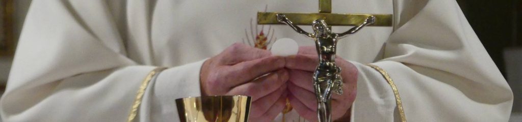 Imagem de um padre segurando uma hóstia durante uma missa.