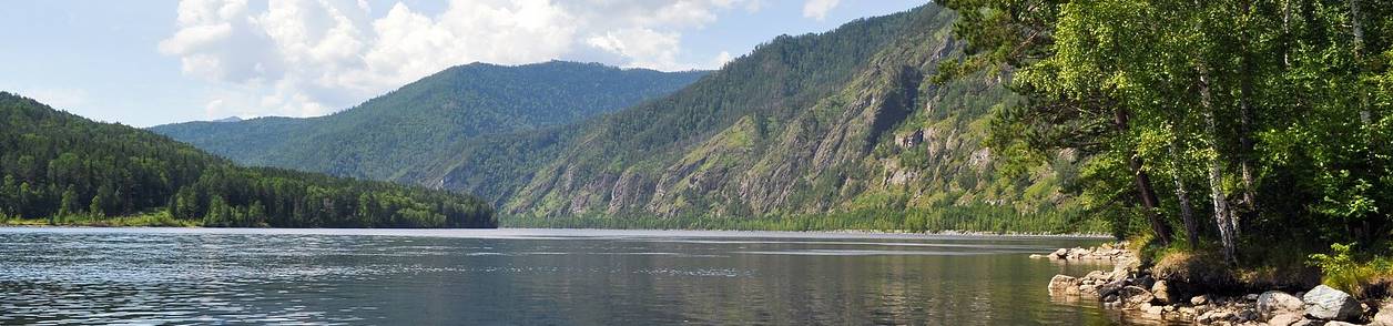 Imagem de um rio cercado por montanhas cobertas por vegetação.