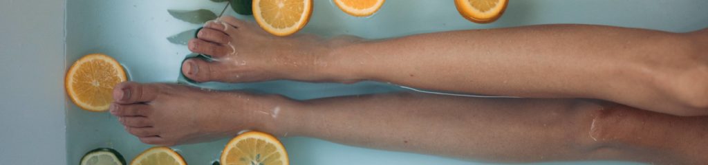 Mulher com pernas esticadas em uma banheira com água.