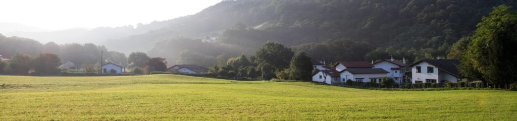 Casas próximas a montanhas e campo de grama.