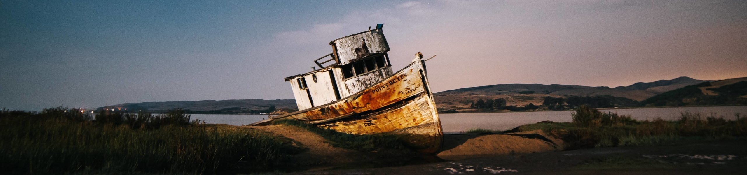 Barco encalhado na areia de um rio.