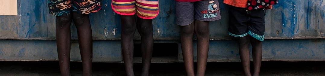 Quatro crianças em frente a uma construção de madeira