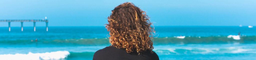 Mulher de cabelos encaracolados na praia de Mission Beach, em San Diego, Califórnia