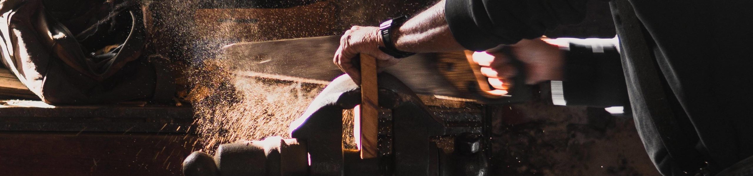 Uma pessoa utiliza um serrote para cortar um pedaço de madeira