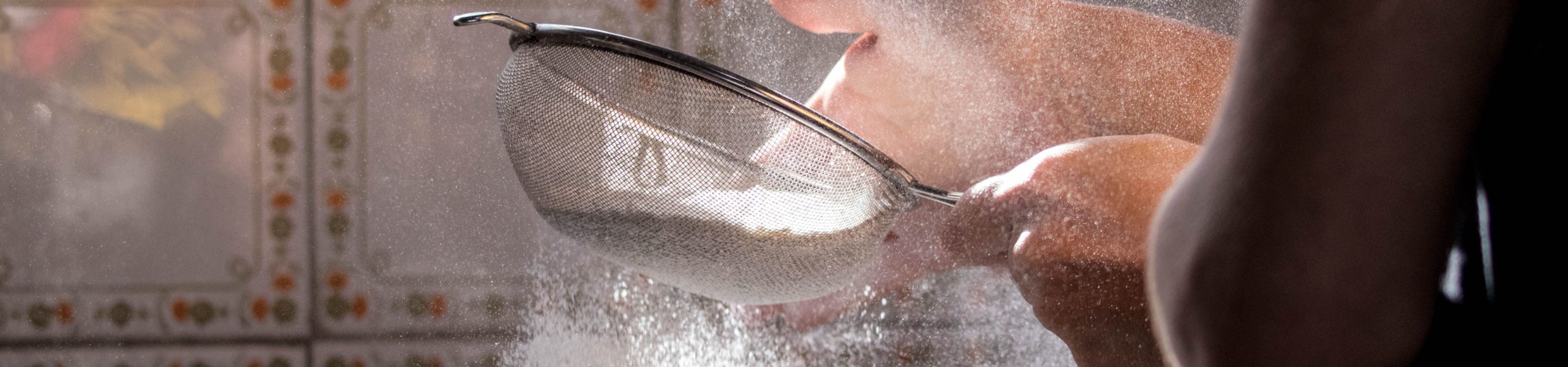 Uma pessoa peneirando farinha de trigo