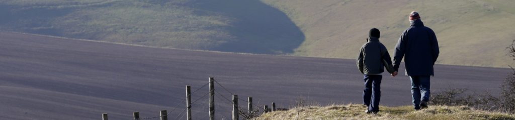 Pai e filho caminhando em uma área de montanhas