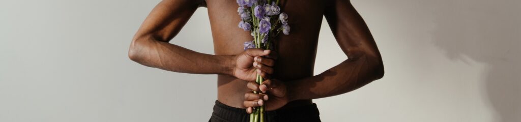Homem de costas segurando uma planta do gênero delfínio