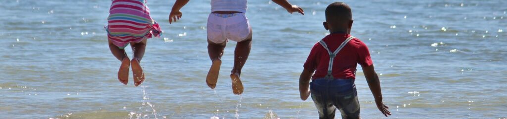 Três crianças brincando na praia