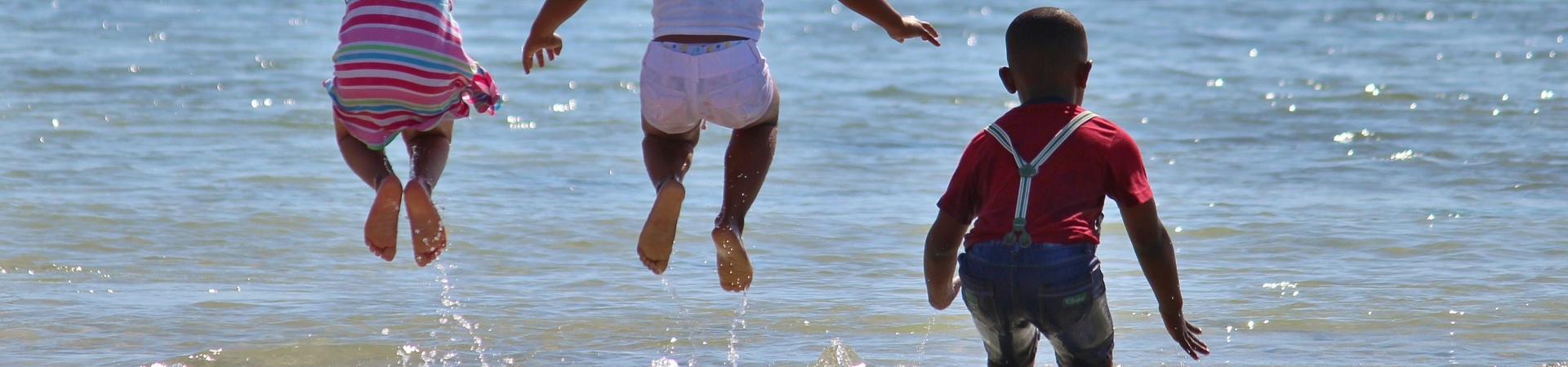 Três crianças brincando na praia