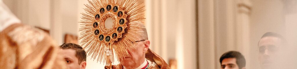 Padre segurando um ostensório de metal dourado