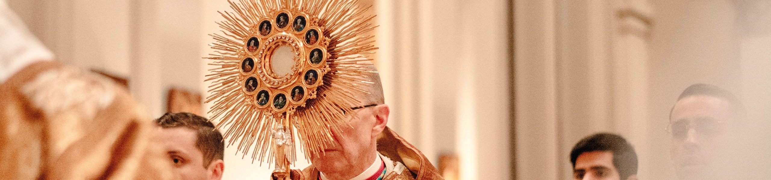 Padre segurando um ostensório de metal dourado